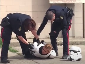 Screengrab from a video that shows Lethbridge, Alta., police officers forcing a woman, dressed as a Stormtrooper for a Star Wars-related restaurant promotion, on her stomach after mistaking a toy blaster for a gun.