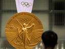 A man takes pictures of a large-scale reproduction of the Tokyo 2020 Olympic Games gold medal, in Tokyo on July 14, 2021.