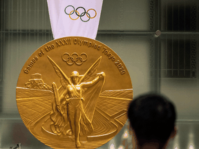 A man takes pictures of a large-scale reproduction of the Tokyo 2020 Olympic Games gold medal, in Tokyo on July 14, 2021.