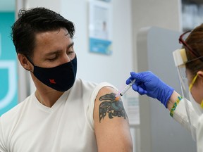 Prime Minister Justin Trudeau watches as he receives his second dose of COVID-19 vaccine from pharmacist Zaineb Hassan at a pharmacy in Ottawa on July 2, 2021.