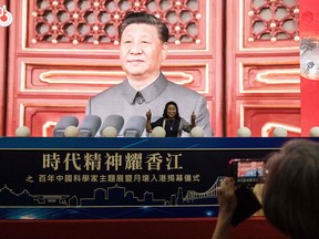 A woman poses for a photo in front of a large screen showing Chinese President Xi Jinping, at an exhibition celebrating the 100th anniversary of the founding of the Communist Party of China, at the Hong Kong Convention Centre on July 8, 2021. This month marks the first time high-profile events have been put on for a CCP anniversary in Hong Kong.