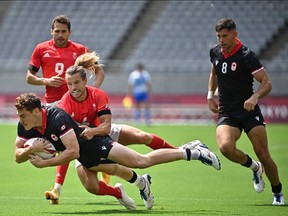 Canada's Phil Berna (L) is tackled by Britain's Tom Mitchell (C) in the men's pool B rugby sevens match between Britain and Canada during the Tokyo 2020 Olympic Games at the Tokyo Stadium in Tokyo on July 26, 2021. (Photo by Ben STANSALL / AFP)