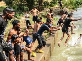 Youths jump into a canal to cool off during a hot summer day on the outskirts of Amritsar on June 23, 2021.