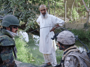 A Canadian soldier, right, speaks to a resident of Bazaar-i-Panjwaii in Afghanistan with the help of an interpreter, left, on August 11, 2008.