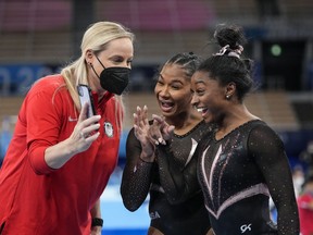 Jordan Chiles, center, and Simone Biles react as a coach shows them photo she had taken during a training session in Tokyo. MUST CREDIT: Washington Post photo for Toni L. Sandys