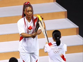 Naomi Osaka of Japan holds the Olympic torch during the opening ceremony.