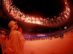 A volunteer reacts during a fireworks display at the end of the  opening ceremony of the Tokyo 2020 Olympic Games.