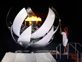 Naomi Osaka of Japan holds the Olympic torch after lighting the Olympic cauldron.