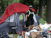 A Toronto police officer watches as city by-law officers moved in on a homeless encampment outside Lamport Stadium on Wednesday July 21, 2021.