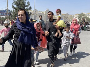 An Afghan family rushes to the Hamid Karzai International Airport as they flee Kabul on Aug. 16, 2021.