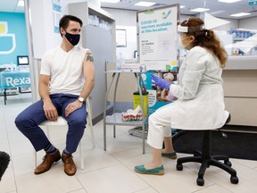 Canada's Prime Minister Justin Trudeau speaks with pharmacist Zaineb Hassan after receiving his second dose of the Moderna coronavirus disease (COVID-19) vaccine at a pharmacy in Ottawa, Ontario, Canada July 2, 2021.