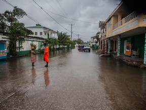 People walk through a flooded street as heavy rain brought by tropical storm Grace hits Haitians just after a 7.2-magnitude earthquake struck Haiti on Aug. 17, 2021 in Les Cayes, Haiti.