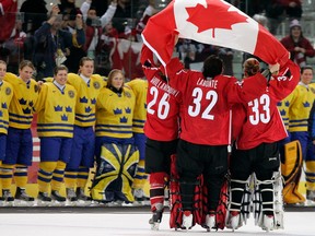 Sarah Vaillancourt #26, Charline Labonte #32, and Kim St-Pierre #33 all of Canada hold the Canadian flag and celebrate their 4-1 victory over Sweden to win the gold medal in women's ice hockey during Day 10 of the Turin 2006 Winter Olympic Games on February 20, 2006 at the Palasport Olimpico in Turin, Italy.  (Photo by Brian Bahr/Getty Images)