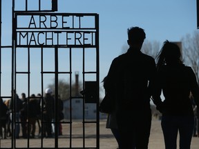 Visitors walk through the infamous "Arbeit Macht Frei" ("Work Makes Free") inscription at the original entrance gate to the former Sachsenhausen concentration camp near Berlin on March 18, 2015 in Oranienburg, Germany.