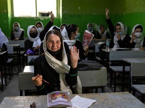 KABUL, AFG- JULY 25: Zinat Karimi, 17, raises her hand during 10th-grade class at the Zarghoona high school on July 25 2021 in Kabul, Afghanistan. The Zarghoona girls high school is the largest in Kabul with 8,500 female students attending classes. The school opened after almost a two months break due to the coronavirus (COVID-19) pandemic. Currently, there is widespread fear that the Taliban who already control around half the country will reintroduce its notorious system barring girls and women from almost all work, and access to education. The Ministry of Education has announced the opening of schools, but there are mixed reports in many areas where the Taliban have taken control or where fighting is ongoing.