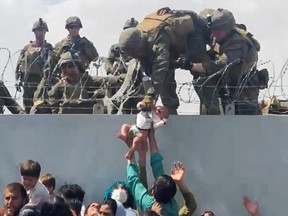 A baby is handed to an American soldier over the perimeter wall of othe airport to be evacuated, in Kabul, Afghanistan, on Aug. 19, 2021.