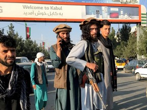 A member of Taliban, centre, stands outside Hamid Karzai International Airport in Kabul on Aug. 16.