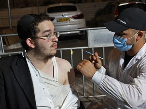 An Israeli health worker administers a third dose of the Pfizer-BioNtech COVID-19 vaccine to Jewish ultra-Orthodox man at a religious neighbourhood in Jerusalem on Aug. 19, 2021.