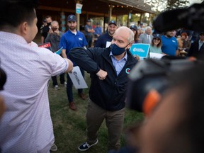 Canada's Conservative Party leader Erin O'Toole elbow bumps with a supporter as he campaigns for the 20th of September General election, at Prarieland Park in Saskatoon, Saskatchewan, Aug. 20, 2021.