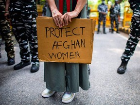 An Afghan woman exile in India displays a placard as she takes part in an anti-Taliban demonstration in New Delhi on August 23, 2021, demanding protection for women in Afghanistan following the Taliban's military takeover of the country.