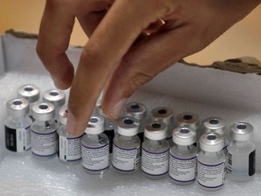 A paramedic with Israel's Magen David Adom medical service gets a vial of the Pfizer-BioNTech Covid-19 vaccine on August 24, 2021 at a vaccination centre in Holon. - Israel lowered the age threshold to receive a third coronavirus booster dose to anyone aged 30 and above, as it continues to battle surging infections.