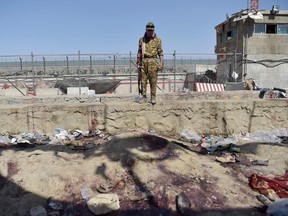 A Taliban fighter stands guard at the site of two powerful explosions, which killed scores of people including 13 US troops on August 26, at Kabul airport on August 27, 2021.