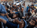 Afghans displaced by the Taliban reach out for aid from a local Muslim organization at a makeshift camp on August 10, 2021 in Kabul.