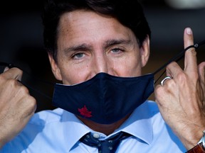 Prime Minister Justin Trudeau takes off his protective face mask  in Longueuil, Quebec, Canada August 16, 2021.