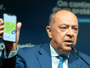 Quebec Health Minister Christian Dube shows an app on his phone as he announces details of the COVID-19 vaccination passport during a news conference  Tuesday, August 10, 2021  in Montreal.