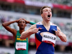 Karsten Warholm of Norway, running beside American Rai Benjamin, reacts after crossing the line to win gold in the men's 400m hurdles in world record time. REUTERS/Lucy Nicholson