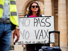 A protestor holds a placard during a demonstration called by the "yellow vests" (gilets jaunes) movement against France's restrictions, including a compulsory health pass, to fight the coronavirus disease (COVID-19) outbreak in Paris, France, August 4, 2021.