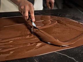 Chef Jose Ramon Castillo is pictured tempering chocolate (spreading it on a marble surface and handling it to lower the temperature gradually) at his chocolate factory in Mexico City, on April 19, 2017