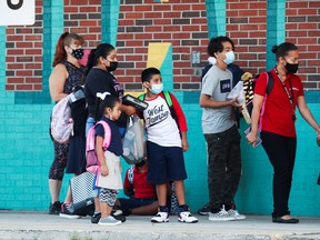 Parents and children wear masks outside as they prepare to enter West Tampa Elementary School on Aug. 10, the first day of school in Florida.