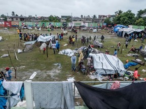 People make repairs and create shelter, after spending the night outside in the aftermath of the earthquake, facing the severe inclement weather of Tropical Storm Grace near Les Cayes, Haiti on August 17, 2021.