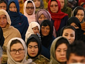 A Hazara woman (C) holds her child as she with others attend an event on International Women's Day in Bamiyan Province on March 8, 2021.