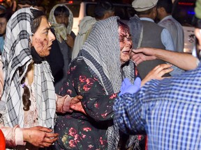 Wounded women arrive at a hospital after two suicide bombings killed at least 60 Afghan civilians and 13 U.S. troops outside the airport in Kabul, where large crowds of people trying to flee Afghanistan had gathered, on Aug. 26, 2021.