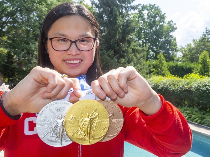  Maggie Mac Neil as she is photographed with her set of gold, silver, and bronze medals from swimming at the Tokyo Olympics in front of the pool her family installed to teach her to swim in London, Ont.