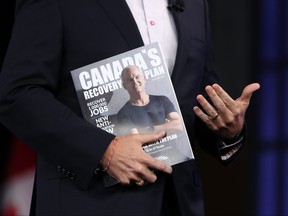 Erin O'Toole holds the Conservative Party's magazine featuring his recovery plan during a campaign event in Ottawa on Mon. Aug. 16.