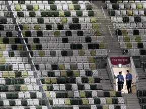 Security guards in a sea of empty seats during the Opening Ceremony for the Olympic Games at Tokyo Olympic Stadium on July 23. No fans were allowed to attend.