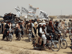 Taliban supporters carry the Taliban’s signature white flags in the Afghan-Pakistan border town of Chaman, Pakistan in July. The Taliban has been seizing key entry points.