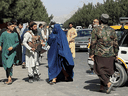 Taliban forces block the roads around the Kabul airport, while a woman passes by, August 27, 2021. After Canada announced its last flight out of Afghanistan, many cooks, guards and translators who had helped Canadians were left stranded.
