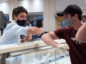 Justin Trudeau, elbow taps with a staff member at the Cows Creamery in Charlottetown, Prince Edward Island, during campaigning August 22, 2021.