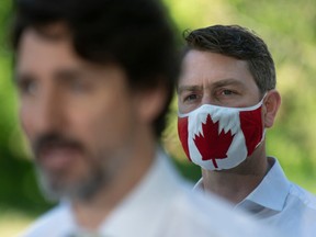 Local Member of Parliament William Amos wear a Canadian flag mask as Prime Minister Justin Trudeau speaks during a news conference in Chelsea , Que.Friday June 19, 2020.