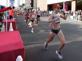 Canada's Malindi Elmore (R) drinks water while competing in the women's marathon final during the Tokyo 2020 Olympic Games at the Sapporo Odori Park in Sapporo on August 7, 2021.