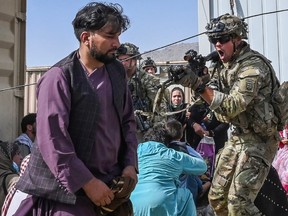 A US soldier (C) point his gun towards an Afghan passenger at the Kabul airport in Kabul on August 16, 2021, after a stunningly swift end to Afghanistan's 20-year war, as thousands of people mobbed the city's airport trying to flee the group's feared hardline brand of Islamist rule.