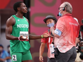 Divine Oduduru of Team Nigeria talks with a track official after receiving a disqualification in the Men's 100m.