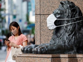 A statue of a lion wears a mask in a file photo from Tokyo taken on Aug. 5, 2021. Three infectious disease specialists write that valid scientific debate on COVID-19 has been gagged by those who deem it "misinformation."