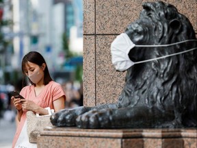 A woman wearing protective face mask stands next to a masked lion statue in Ginza shopping area, amid the coronavirus disease (COVID-19) outbreak in Tokyo, Japan August 5, 2021. REUTERS/Androniki Christodoulou