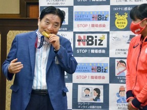 Nagoya city Mayor Takashi Kawamura bites the Tokyo 2020 Olympic Games gold medal of the softball athlete Miu Goto during a ceremony in Nagoya, central Japan, August 4, 2021, in this photo taken by Kyodo.