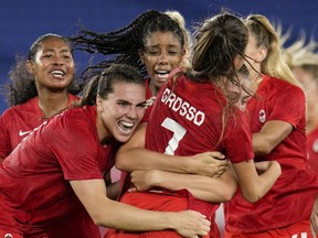 Teammates embrace Canada's Julia Grosso after she scored the winning goal against Sweden in the women's soccer match for the gold medal at the 2020 Summer Olympics, Friday, Aug. 6, 2021, in Yokohama, Japan.
